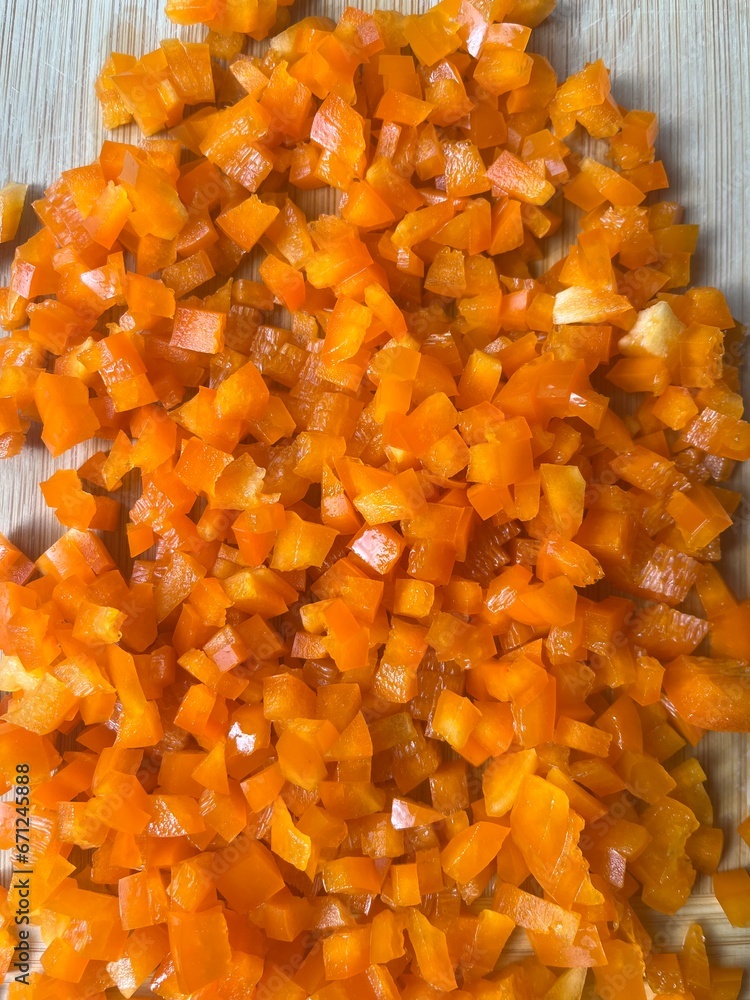 Pile of finely diced orange bell pepper on wooden cutting board Pile of finely diced orange bell pepper on wooden cutting board