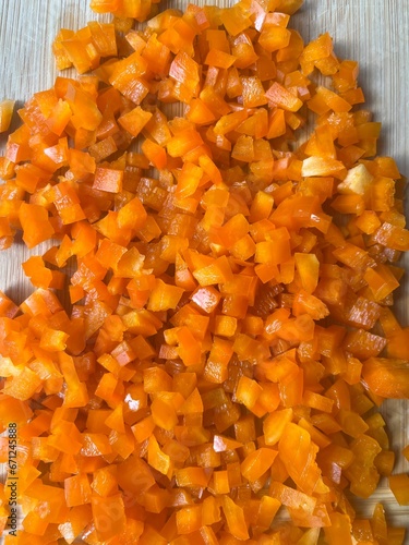 Pile of finely diced orange bell pepper on wooden cutting board