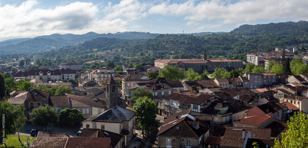 Vista panorámica del pueblo de Allaritz en Orense, con tejados de casas, campanario de la iglesia, rodeado de montañas y árboles verdes, verano de 2021, España.