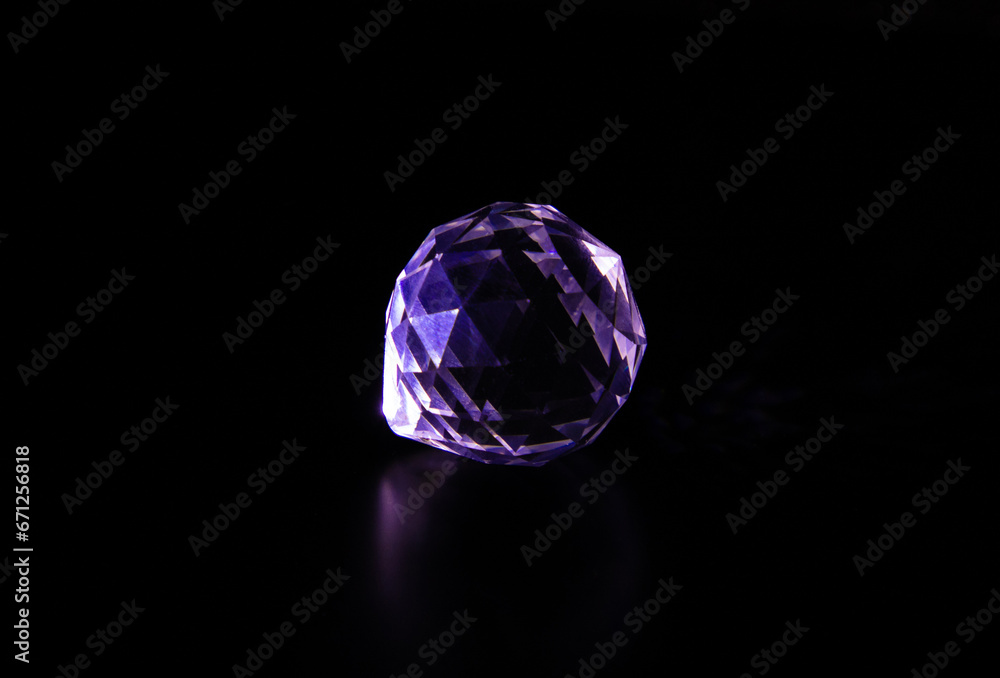 A gemstone crystal sparkling on a dark background. Diamond imitation on a black background A gemstone crystal sparkling on a dark background. Diamond imitation on a black background