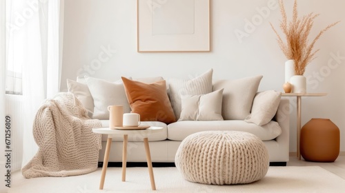 Knitted pouf near white fabric sofa with blanket and terra cotta pillows Scandinavian hygge style home interior design of modern