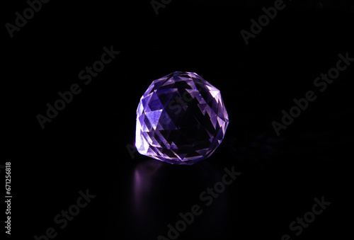 A gemstone crystal sparkling on a dark background. Diamond imitation on a black background