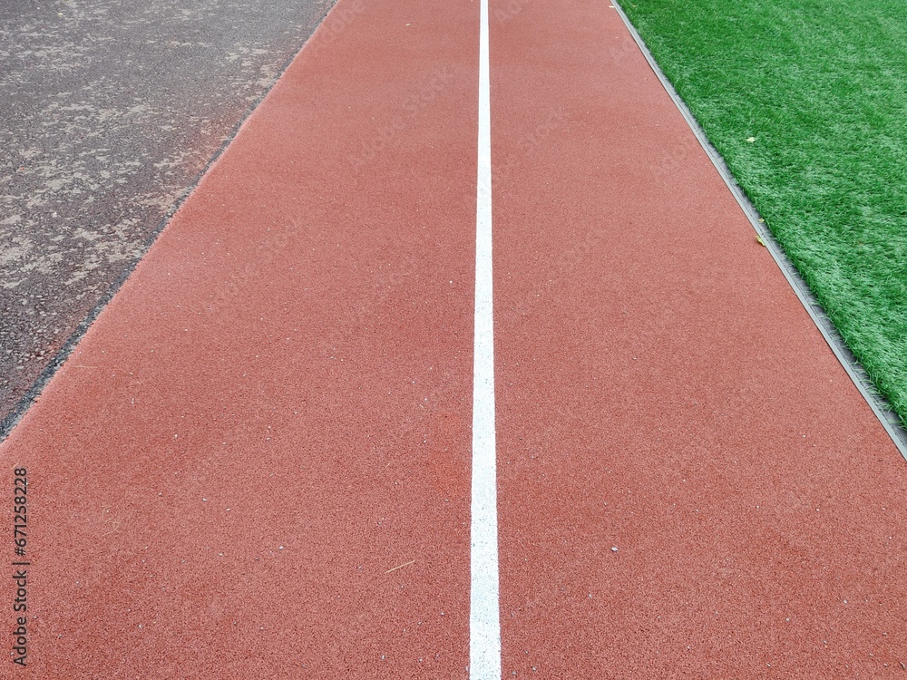 Fototapeta premium The treadmill at the school stadium in close-up. A public sports ground with a football field and athletics tracks. Improvement of places for sports. Everything for a healthy lifestyle