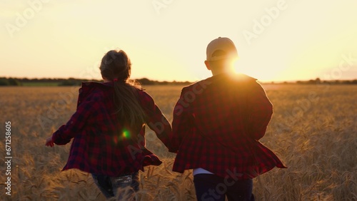 Happy children  boy  girl  run around wheat field  holding hands  sun day. Happy family outdoor. Girl  boy children of farmers run together  dream of flying  nature. Story of childhood friendship.