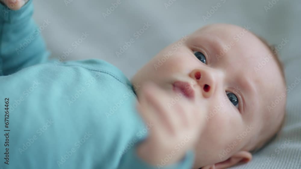 Cute two-month-old baby in blue clothes looks into camera, slow motion. Active newborn boy lies on the sofa and moves his arms. Shooting from the upper angle of a chubby male baby. Beautiful infant. Cute two-month-old baby in blue clothes looks into camera, slow motion. Active newborn boy lies on the sofa and moves his arms. Shooting from the upper angle of a chubby male baby. Beautiful infant.