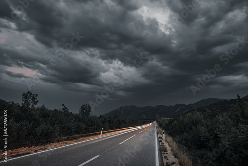 Asphalt road panorama in countryside on cloudy day. Road in forest under dramatic cloudy sky. Image of wide open prairie with a paved highway stretching out as far as the eye can see.