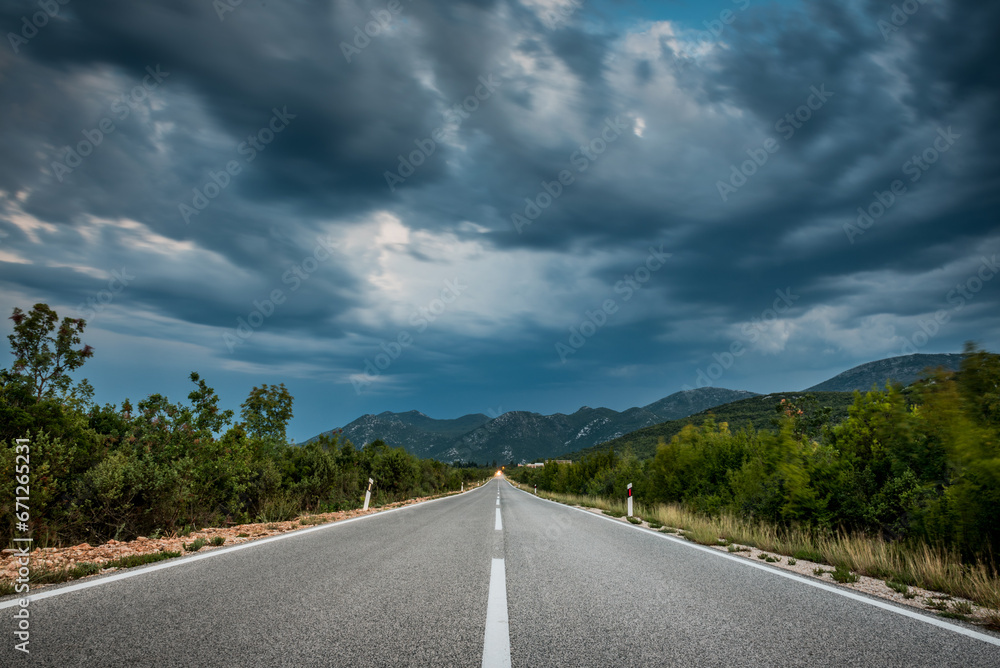 Asphalt road panorama in countryside on cloudy day. Road in forest under dramatic cloudy sky. Image of wide open prairie with a paved highway stretching out as far as the eye can see. Asphalt road panorama in countryside on cloudy day. Road in forest under dramatic cloudy sky. Image of wide open prairie with a paved highway stretching out as far as the eye can see.