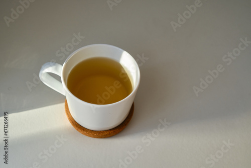 White cup with coffee or tea on the bed. Cozy morning photo. The concept is cozy and warm. Place for text