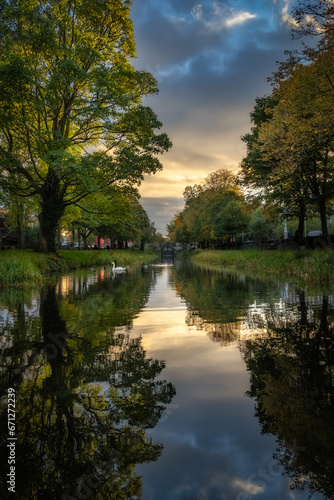 Fototapeta Naklejka Na Ścianę i Meble -  Beautifull and moody sunset at Grand Canal seen from lock C2 with aquatic birds, trees and clouds reflecting on the water, Dublin city centre, Ireland