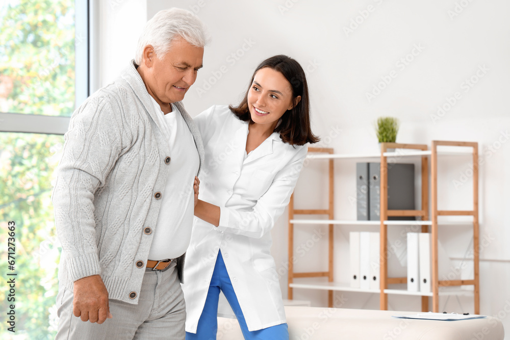 Fototapeta premium Female physiotherapist working with senior patient in rehabilitation center, closeup