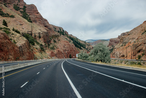 Scenic highway among red canyons on a sunny autumn day. Beautiful landscape with high red mountains and green bushes. Echo Canyon, Utah, USA in fall © Liudmila