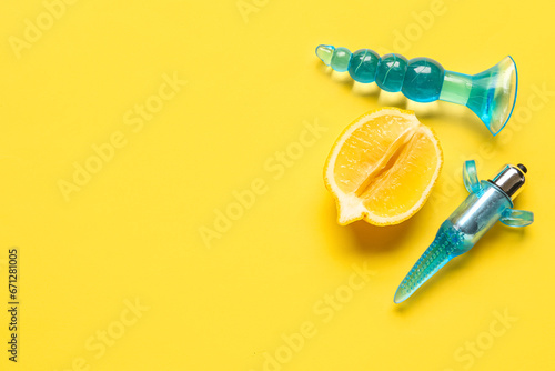 Different anal plugs from sex shop and half of tasty lemon on yellow background © Pixel-Shot