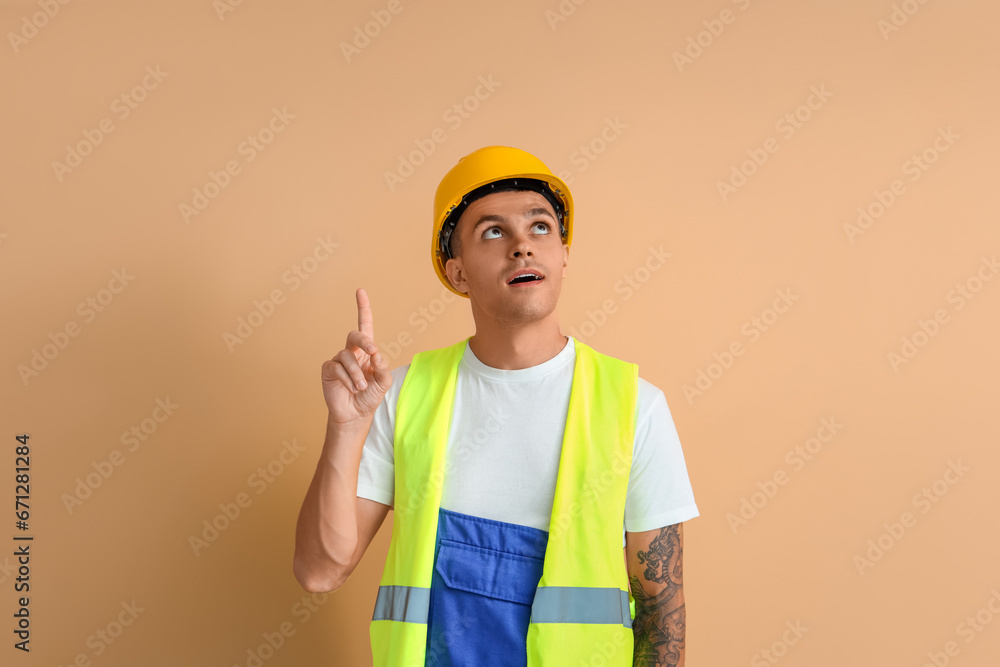 Male worker pointing at something on beige background Male worker pointing at something on beige background
