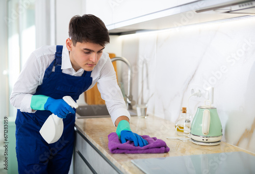 Male professional cleaner cleaning the kitchen countertop