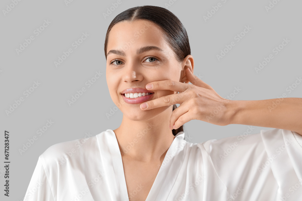 Beautiful young woman massaging her face on light background, closeup Beautiful young woman massaging her face on light background, closeup