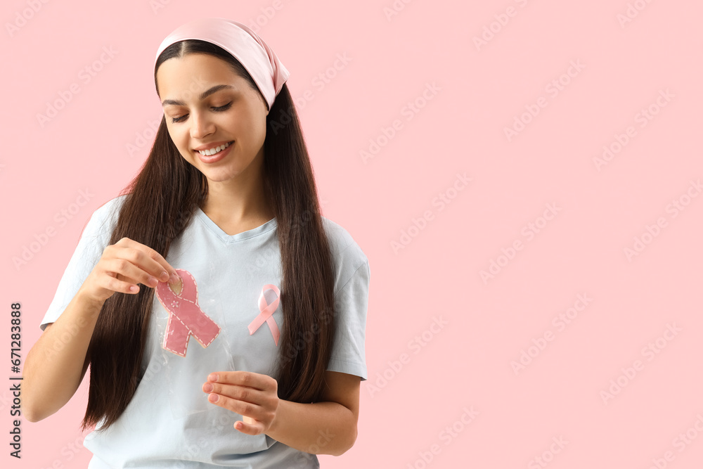 Young woman bagging cookie on pink background. Breast cancer awareness concept Young woman bagging cookie on pink background. Breast cancer awareness concept