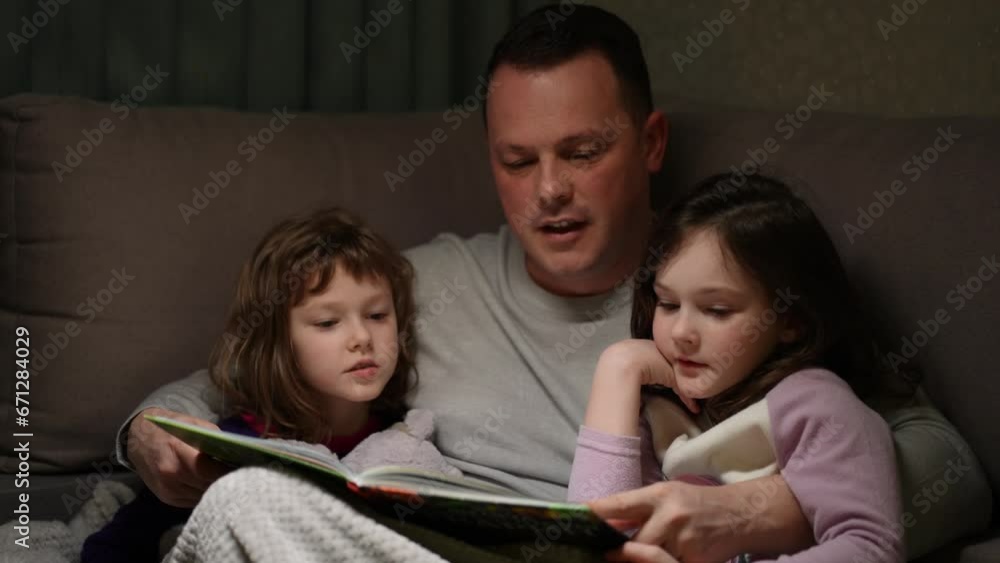 A father reads a book to his children before bed A father reads a book to his children before bed