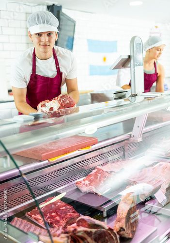 Knowledgeable male butcher proudly showcases finest cuts on his stand, guiding customer's choice.