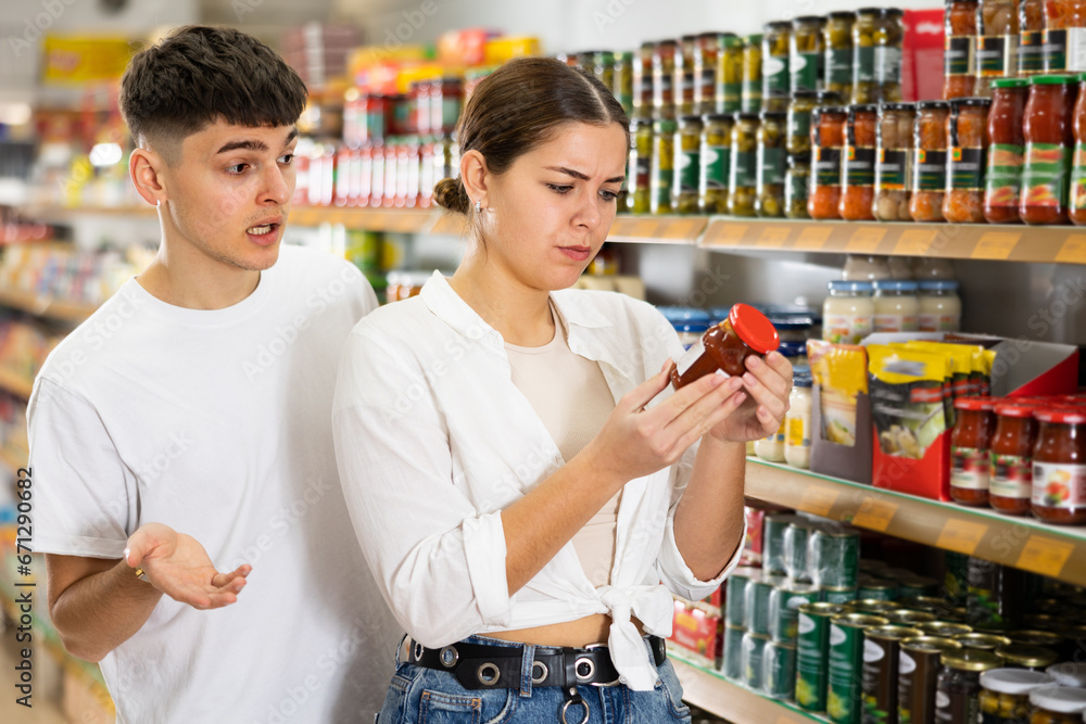 Young woman looking to buy preserved food in supermarket