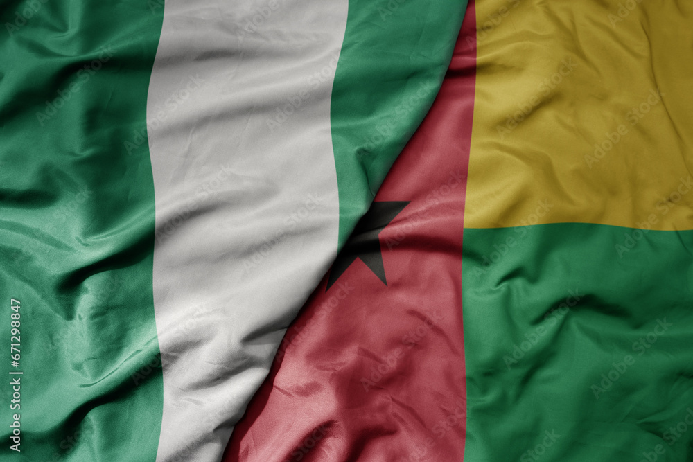 big waving national colorful flag of nigeria and national flag of guinea bissau .