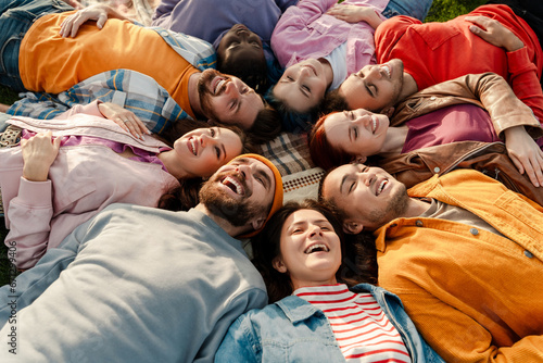 Top view group of smiling multicultural relaxing, chilling, lying on green grass in park. Diversity, friendship, vacation, travel concept 
