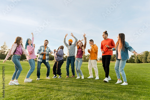 Big group of happy stylish multiracial friends wearing colorful clothing dancing on corporate party in park. Diversity  friendship  positive lifestyle  concept   