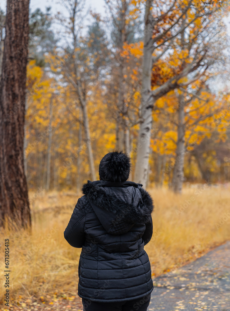 Woman standing in front of golden yellow fall leaves in forest Woman standing in front of golden yellow fall leaves in forest