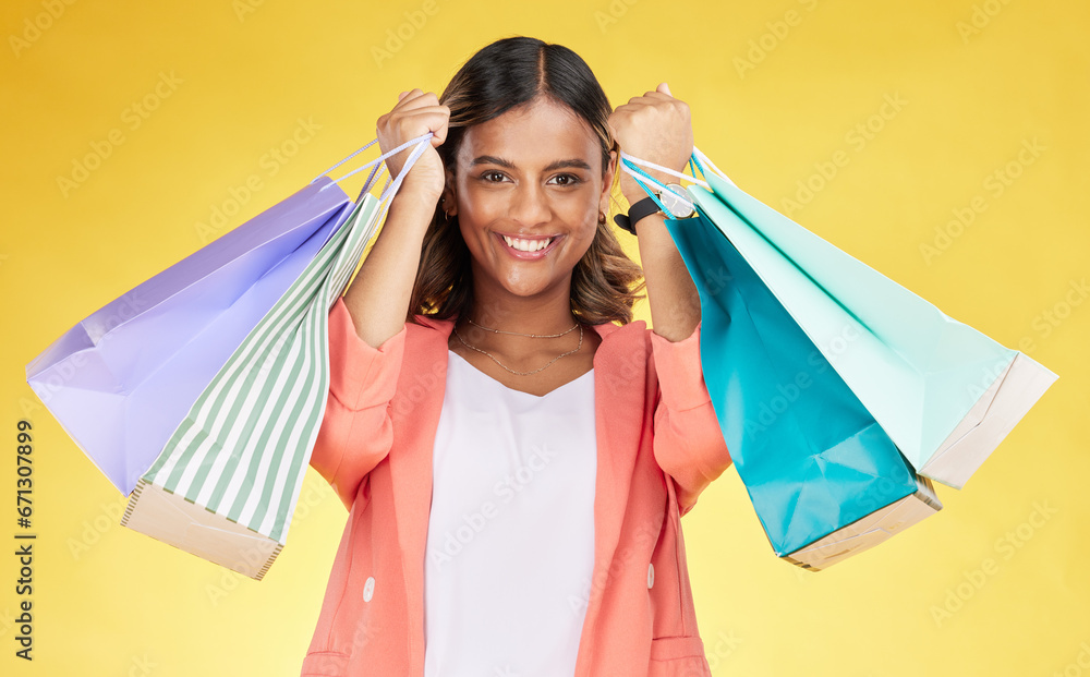 Portrait, woman and smile for shopping of bag in studio, retail deal or financial freedom on yellow background. Indian customer, gift or present at fashion boutique, discount store or sales promotion
