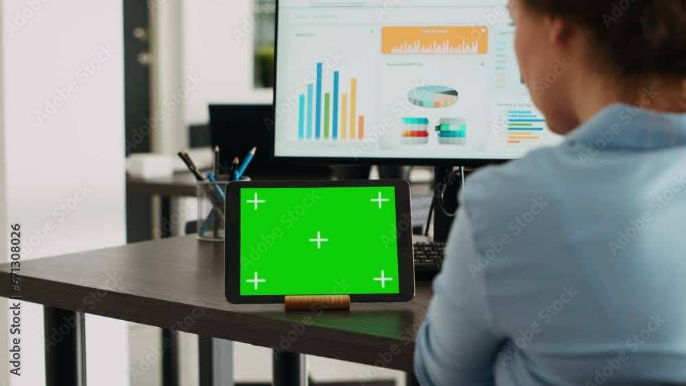 Company employee having tablet on desk with greenscreen display in startup agency office, using blank mockup template and isolated chromakey layout. Woman looking at digital web app on device. Company employee having tablet on desk with greenscreen display in startup agency office, using blank mockup template and isolated chromakey layout. Woman looking at digital web app on device.