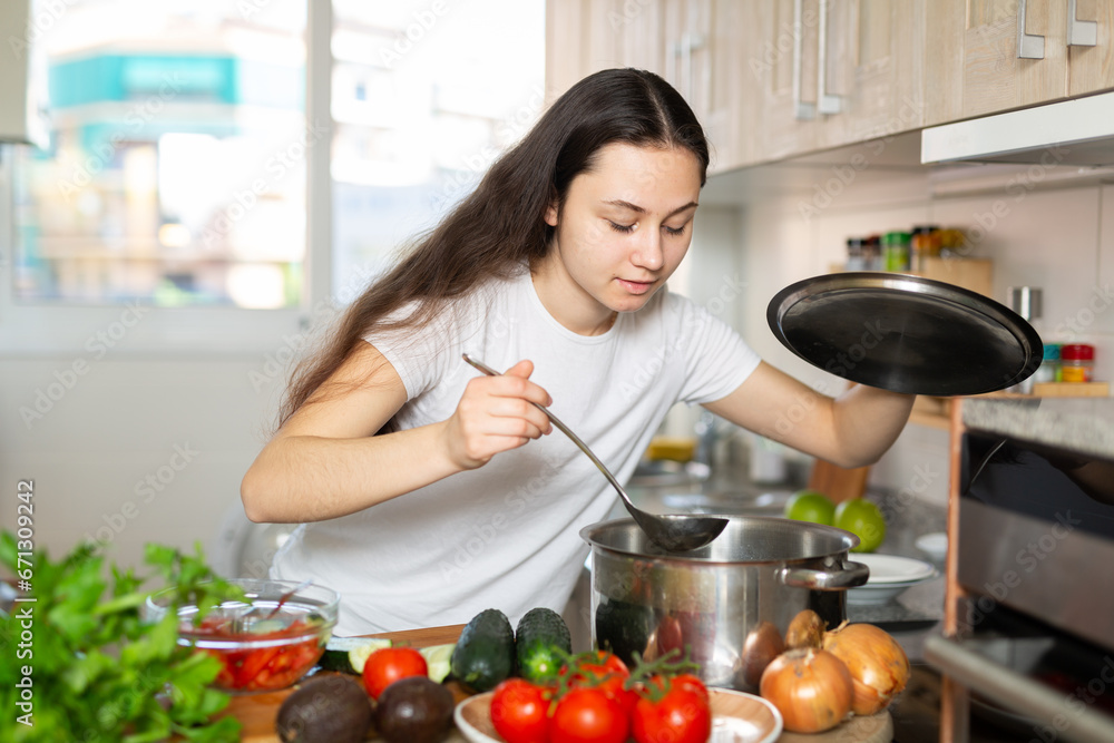 Positive woman holding cooking pot on kitchen