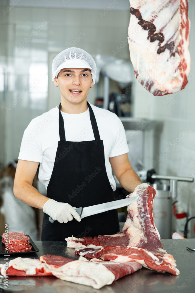With precision, man behind counter prepares and presents various cuts of meat.
