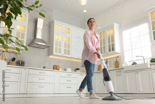 Wallpaper Mural Happy woman cleaning floor with steam mop in kitchen at home, low angle view Torontodigital.ca