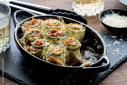 A baking dish of zucchini roll ups with parmesan cheese on top.