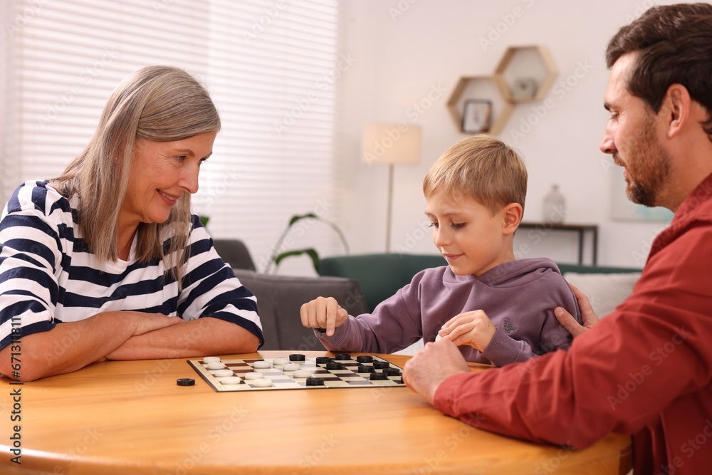 Family playing checkers at wooden table in room Family playing checkers at wooden table in room