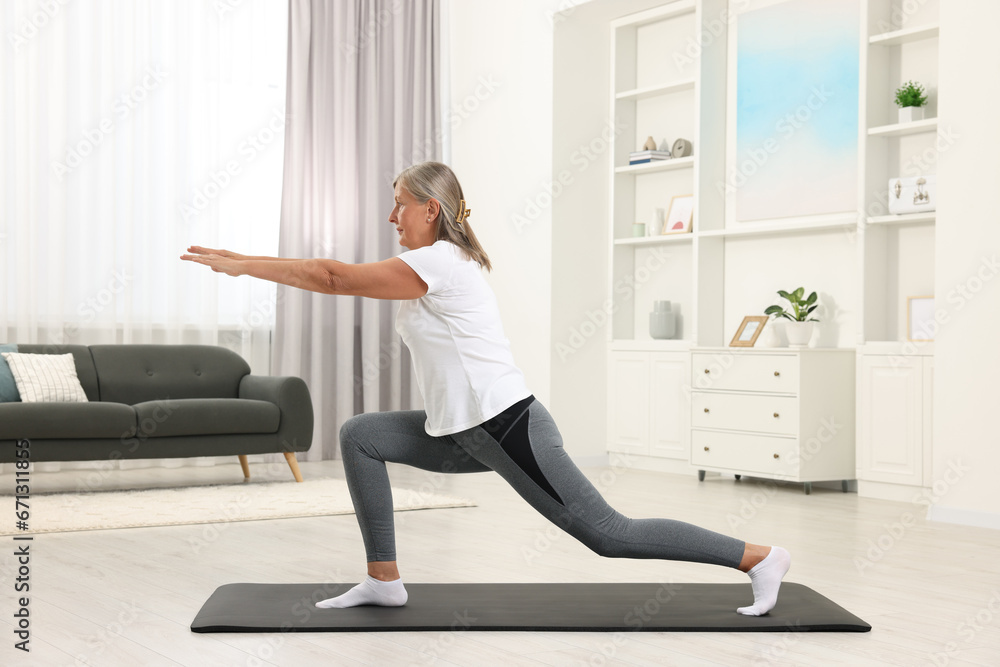 Senior woman practicing yoga on mat at home