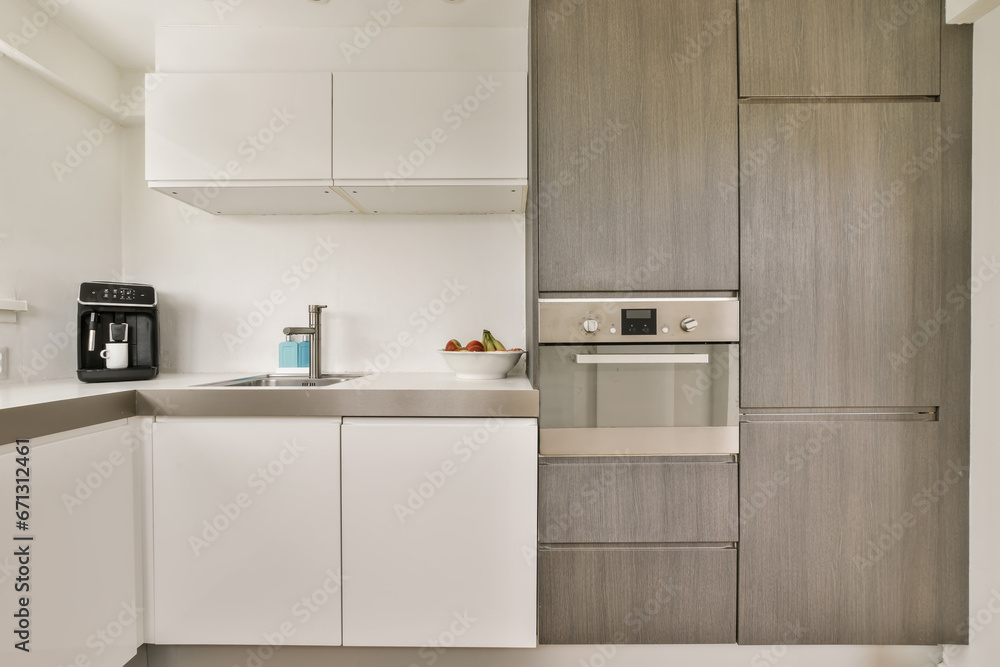 a kitchen area with white cabinets and gray countertops on either side, one has a coffee machine in the corner a kitchen area with white cabinets and gray countertops on either side, one has a coffee machine in the corner