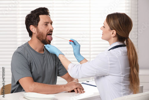 Doctor taking throat swab sample from man`s oral cavity indoors photo