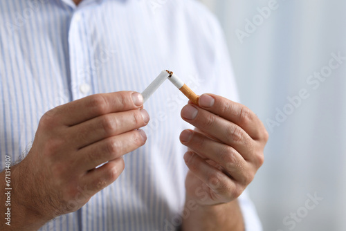 Stop smoking concept. Man breaking cigarette on light background  closeup