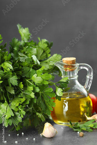 Fresh parsley, oil and other products on grey table, closeup
