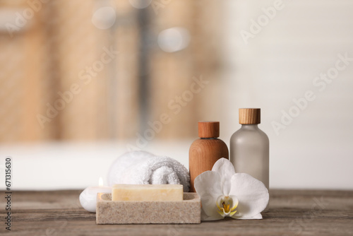 Composition with spa products, beautiful flower and candle on wooden table against blurred background, space for text