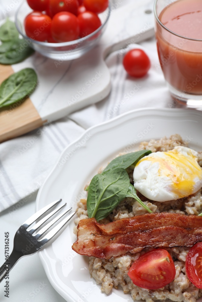 Delicious boiled oatmeal with poached egg, bacon and tomato served on table, closeup Delicious boiled oatmeal with poached egg, bacon and tomato served on table, closeup