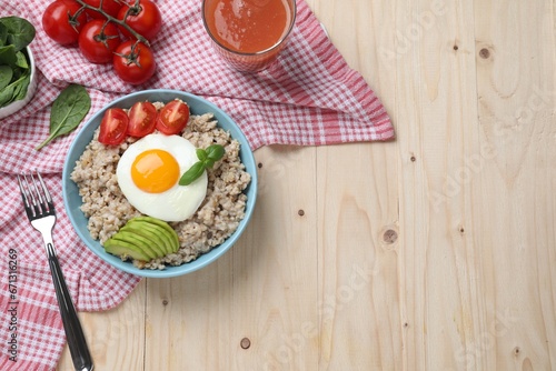 Delicious boiled oatmeal with fried egg, bacon, avocado and tomato served on wooden table, flat lay. Space for text