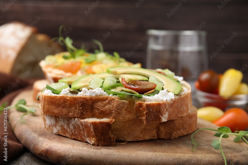 Tasty vegan sandwich with avocado, tomato and spinach on wooden table, closeup