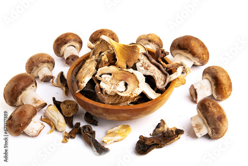 Assorted edible dried mushrooms in a wooden bowl isolated on a white background.