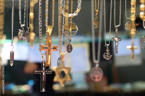varias correntes com símbolos em pingentes em forma de cruz, estrela de david, santos, projéteis, a venda na feira de rua. photo