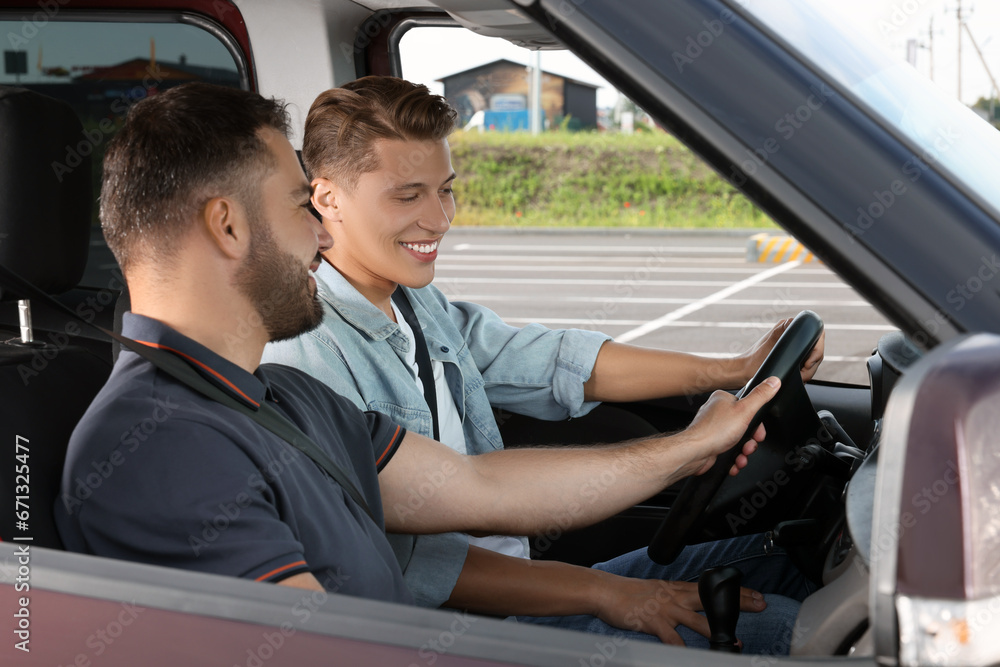 Driving school. Happy student during lesson with driving instructor in car at parking lot Driving school. Happy student during lesson with driving instructor in car at parking lot