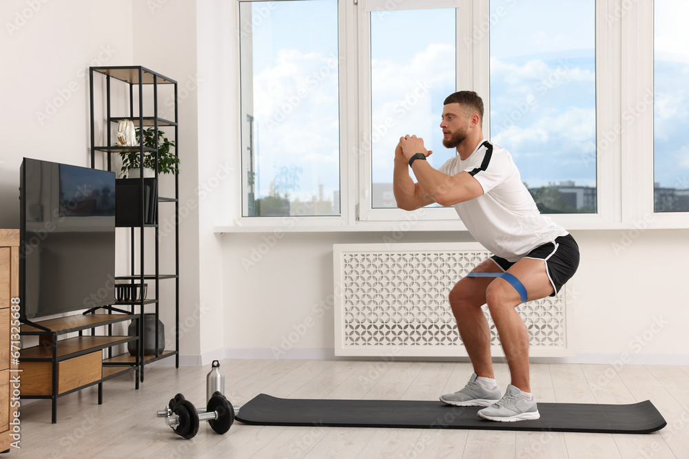 Athletic man doing exercise with elastic resistance band on mat at home Athletic man doing exercise with elastic resistance band on mat at home