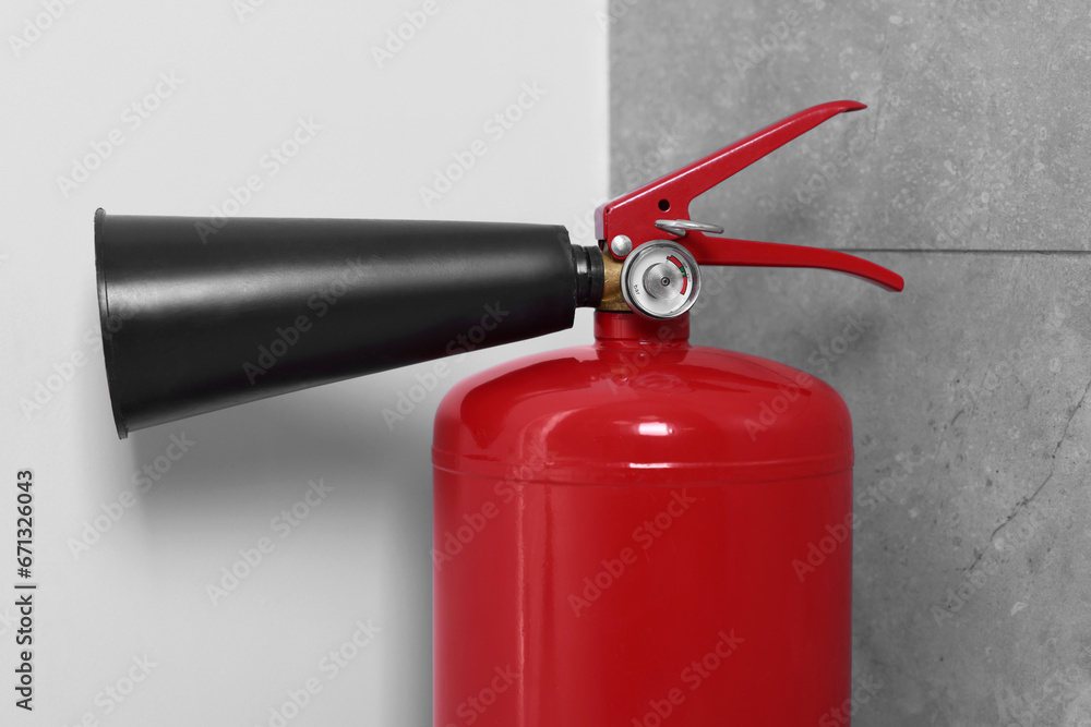 Red fire extinguisher in corner, closeup view Red fire extinguisher in corner, closeup view