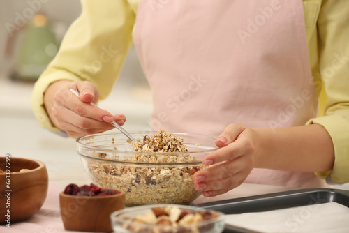 Woman making granola at table in kitchen, closeup