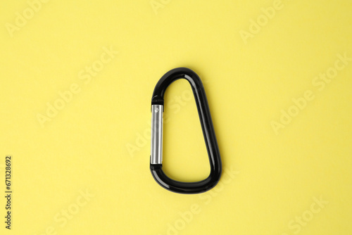 One black carabiner on yellow background, top view photo